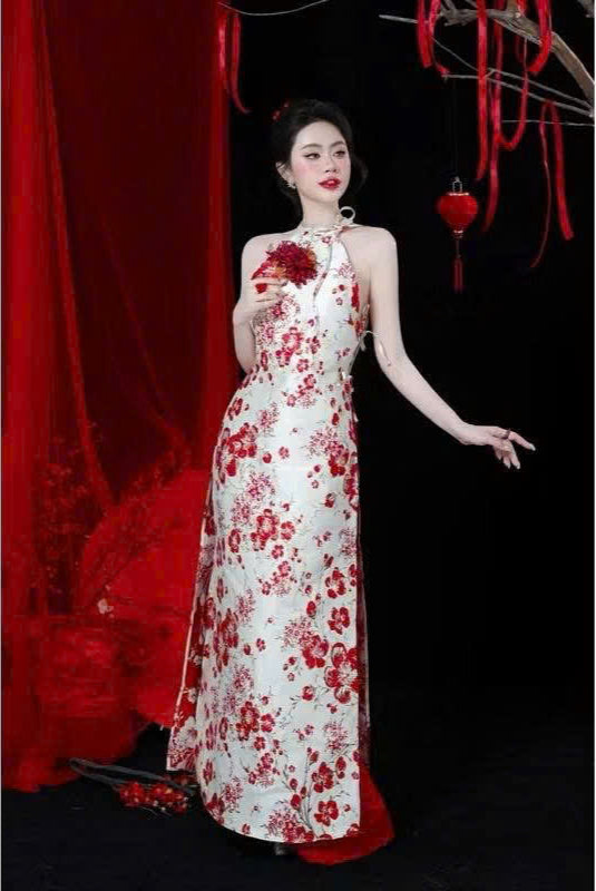 Woman in a white dress with red floral patterns against a dark background with red decorations.